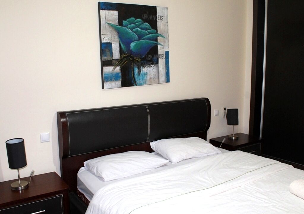 A neatly made bed with white linens in a hotel room.