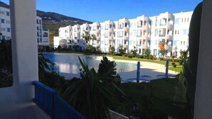 Un hotel con piscina, rodeado de vegetación y montañas al fondo.