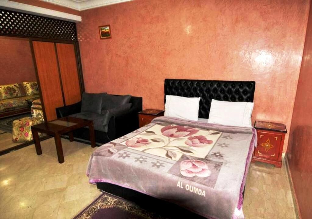 Een hotelkamer met een bed, een bank, een nachtkastje en een decoratief hoofdeinde.
