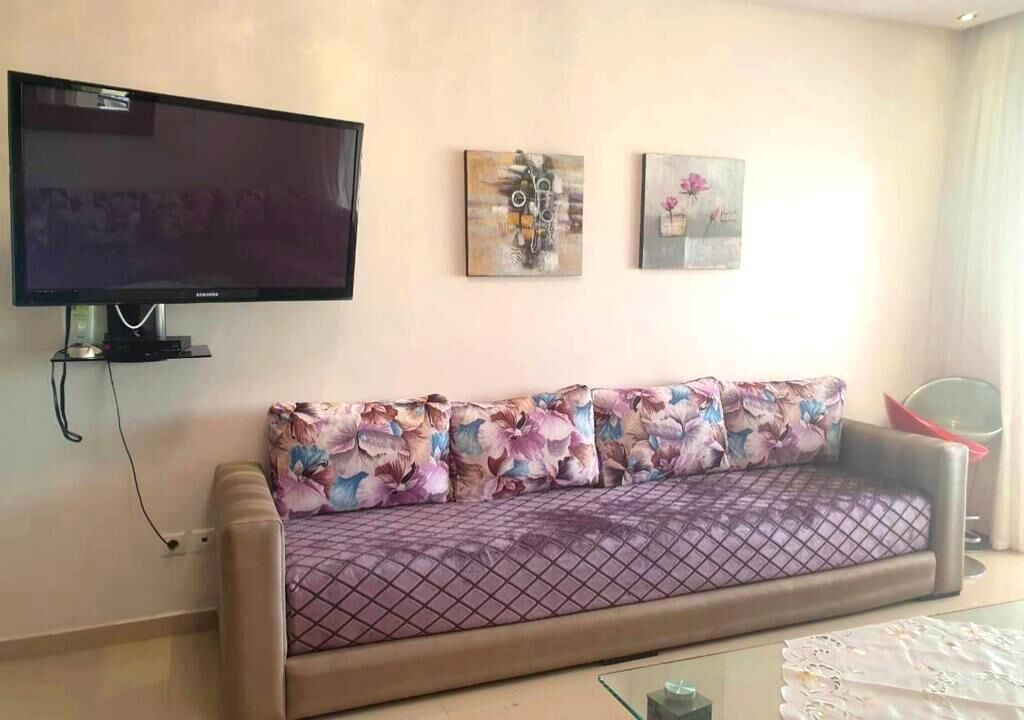 Ein Wohnzimmer mit einer Couch, einem Flachbildfernseher und zwei an der Wand befestigten Bildern.