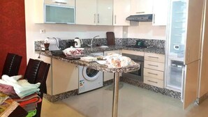 Une cuisine compacte équipée d’un lave-linge, d’un four à micro-ondes et d’un réfrigérateur.