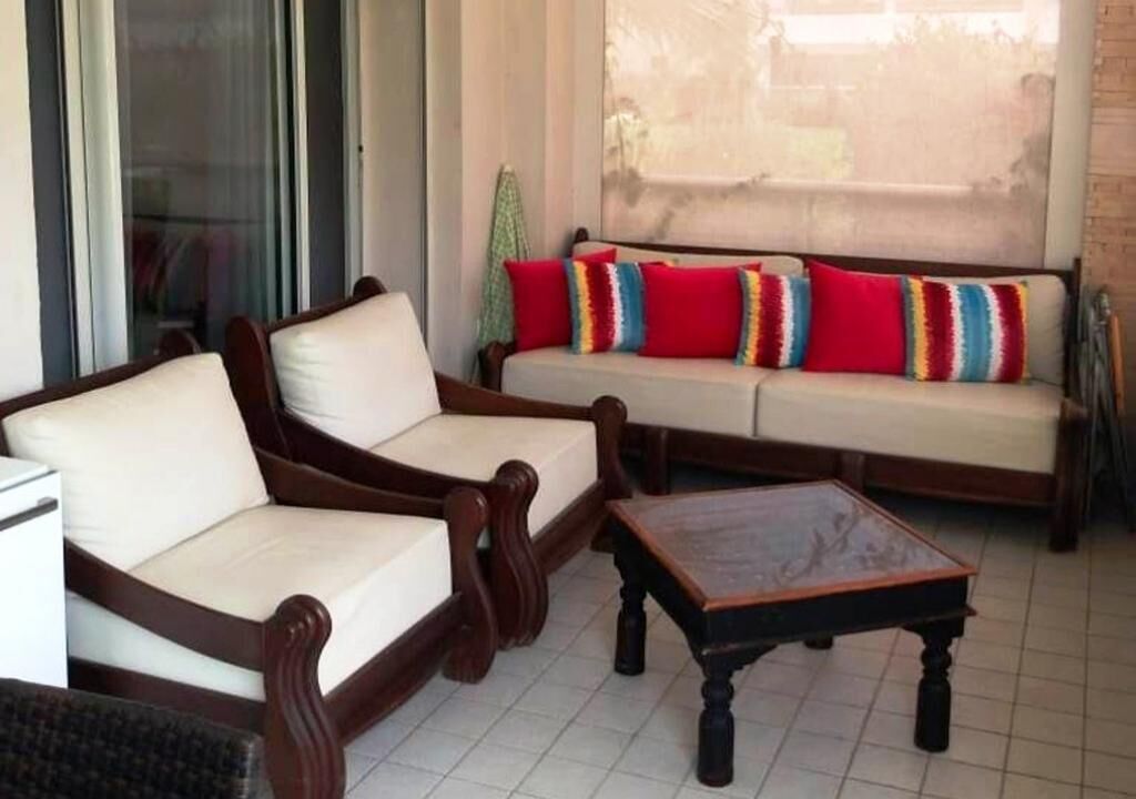 Ein Wohnzimmer mit einer Sofagarnitur, einem Couchtisch und einer Schiebetür aus Glas.