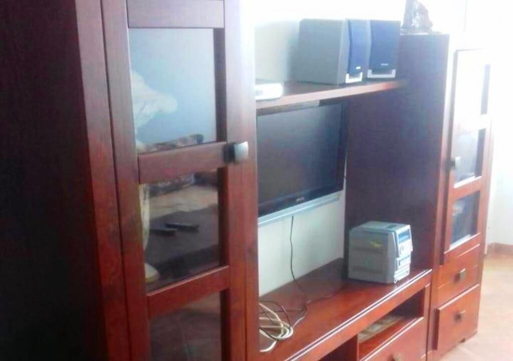 A wooden entertainment center with a flat-screen TV, a stereo system, and a small cabinet.