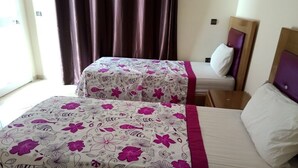 Dos camas individuales con ropa de cama estampada con motivos florales y cabeceros de madera.