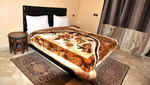 Una camera da letto con un letto, un comodino e un'ampia finestra con tende.
