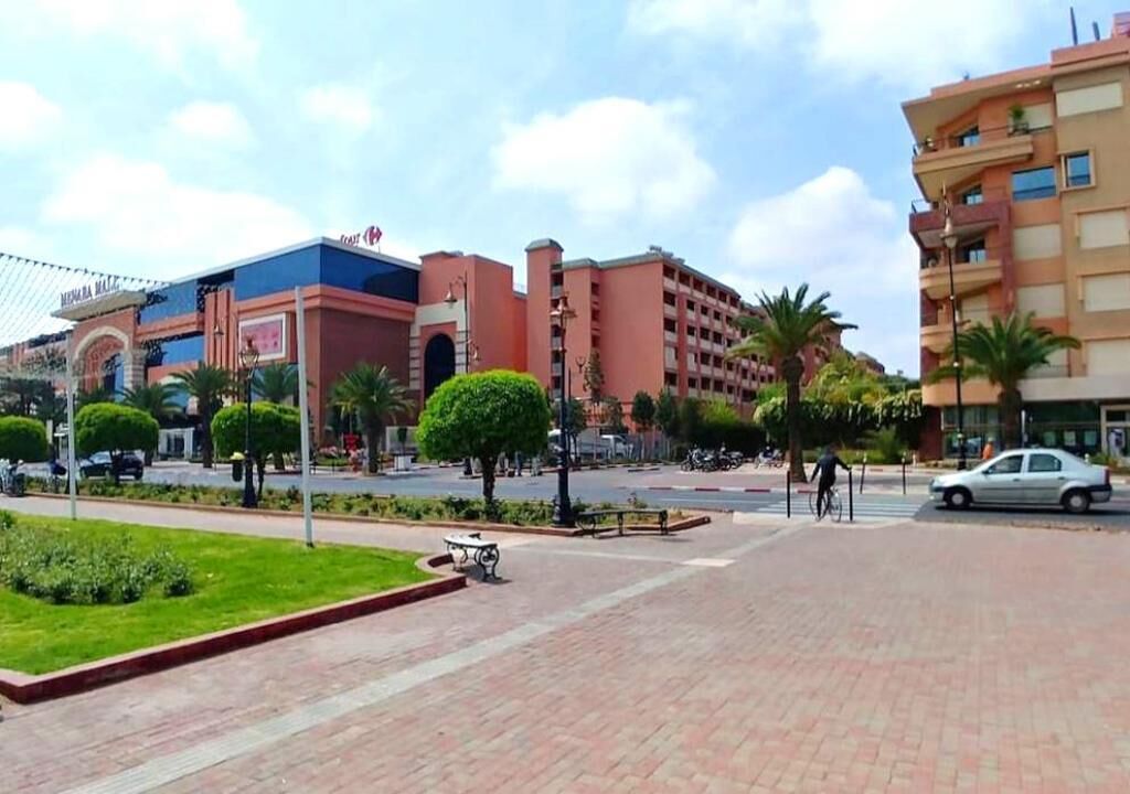 A hotel with a modern design, featuring a prominent entrance and a landscaped courtyard with neatly trimmed bushes and a fountain.