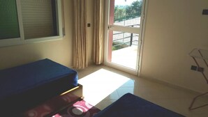 A room with a bed, a window with curtains, and a view of the outside. - Atlantic Ocean Residence 3043 (Asilah)