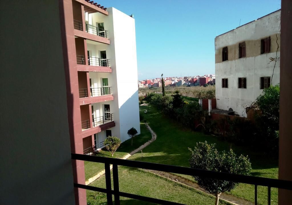 A view from a balcony overlooking a courtyard with buildings in the background.