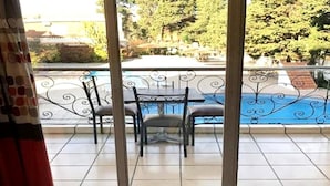 Ein Balkon mit Blick auf einen Swimmingpool, einem Tisch und zwei Stühlen.