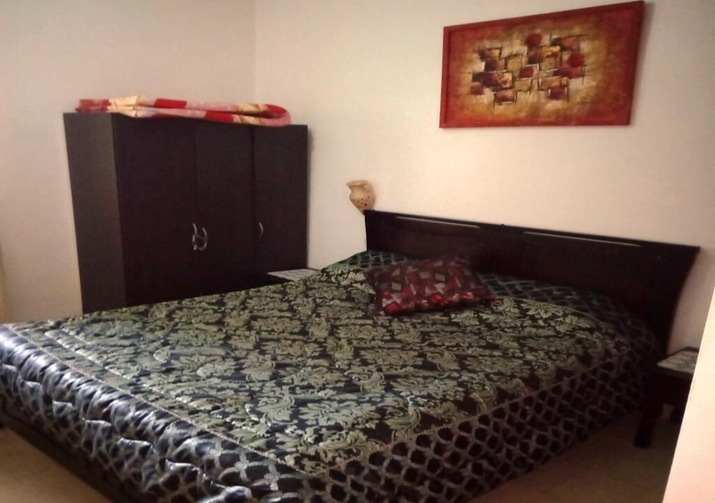 Un dormitorio con cama, armario y un cuadro en la pared.