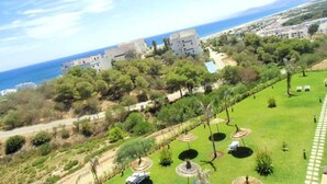 Uma propriedade costeira com vista para o mar, um jardim com vasos circulares e uma paisagem montanhosa.