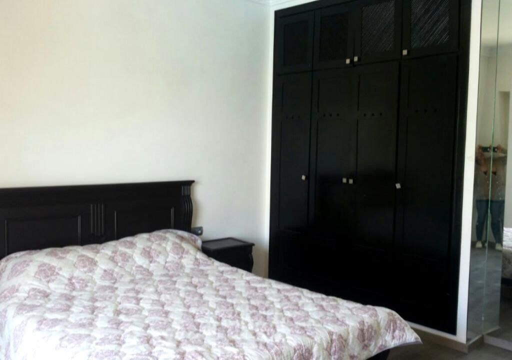 Un dormitorio con cama, mesita de noche y armario.