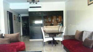 A modern living room with a glass coffee table, a red sofa, and a dining area with a table and chairs. - Residence Marina Agadir 2952 (Agadir)