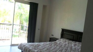 A bedroom with a large bed, a wooden headboard, and a sliding glass door leading to a balcony. - Residence Marina Agadir 2952 (Agadir)
