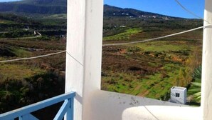Un balcone con vista su un paesaggio collinare, che include una strada e degli edifici in lontananza.