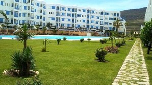 Un hotel con piscina, prato verde e vialetto in pietra.