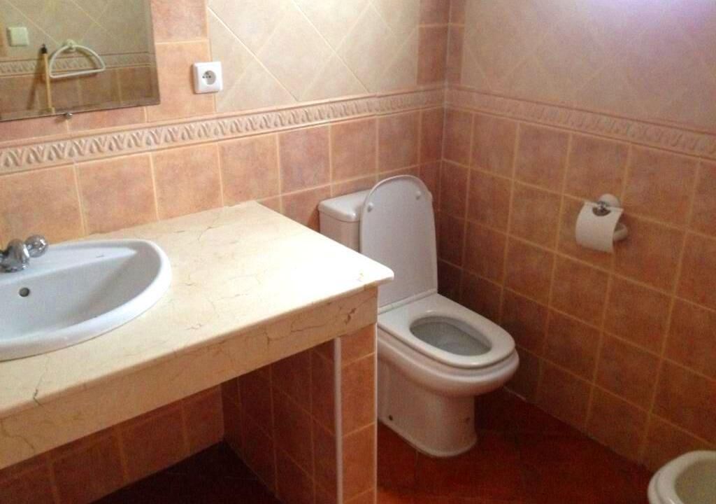 Une salle de bain avec un lavabo, des toilettes et un miroir.
