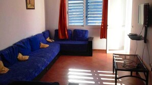 Una stanza arredata con un divano blu, un tavolino e una finestra con tende.