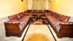 Une pièce comprenant un grand canapé d’angle, une table basse ronde et un tapis à motifs.