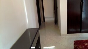 A hallway with a dark wooden door, a small table, and a red patterned ottoman. - Atlantic Ocean Residence 3033 (Asilah)