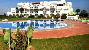 A pool area with lounge chairs and a building with balconies in the background. - The Greens Residence 3625 (SAIDIA)