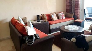 Una sala de estar con sofá, reposapiés y una mesita redonda.