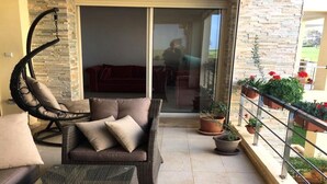 A balcony with a wicker sofa, a hanging chair, and potted plants. - Residence Bellavis Tabznica 2432 (Bouznika)