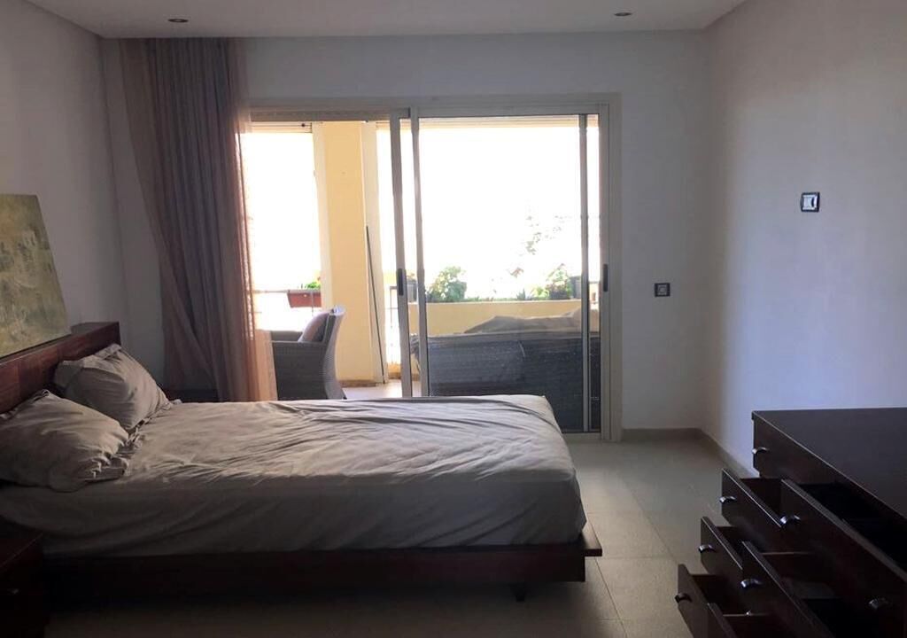 Ein Schlafzimmer mit einem Bett, einem Schminktisch und einer Glastür, die auf einen Balkon führt.