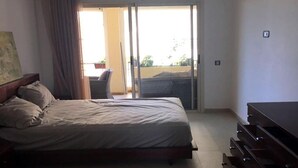 A bedroom with a bed, a dresser, and a sliding glass door leading to a balcony. - Residence Bellavis Tabznica 2432 (Bouznika)