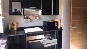 A modern kitchen with black cabinets, a microwave, and a wooden door. - Residence Bellavis Tabznica 2432 (Bouznika)