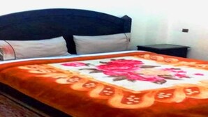Un lit avec une couvre-lit à motifs floraux, une tête de lit sombre et une petite table de chevet.