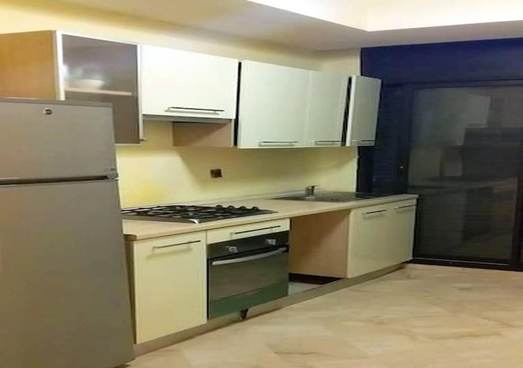 Une cuisine de taille réduite équipée d’un réfrigérateur, d’une cuisinière, d’un four et de placards.