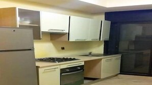 Une cuisine de taille réduite équipée d’un réfrigérateur, d’une cuisinière, d’un four et de placards.