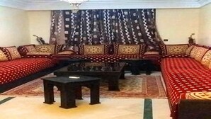 Un salon comprenant un ensemble de canapés, une table basse et des rideaux à motifs.