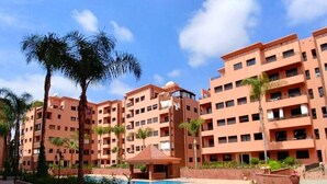 A multi-story hotel with a central courtyard, palm trees, and a swimming pool. - Residence Babylon Marrakech 3367 (Marrakech)