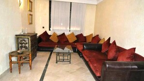 A living room with a red sofa, a small wooden table, and a decorative cabinet. - Residence Babylon Marrakech 3367 (Marrakech)