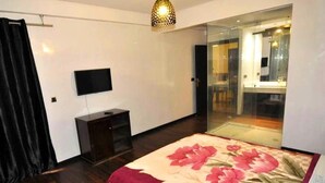 Een slaapkamer met een bed, een televisie, een kledingkast en een glazen deur naar een badkamer.