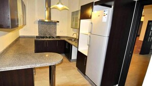 Een moderne keuken met donkere kastjes, een granieten aanrechtblad, roestvrijstalen apparatuur en een centraal kookeiland.