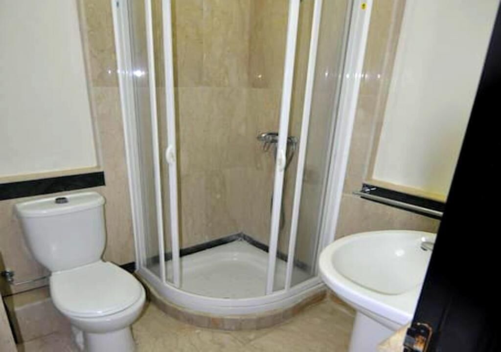 A bathroom with a toilet, a shower enclosure, and a sink.