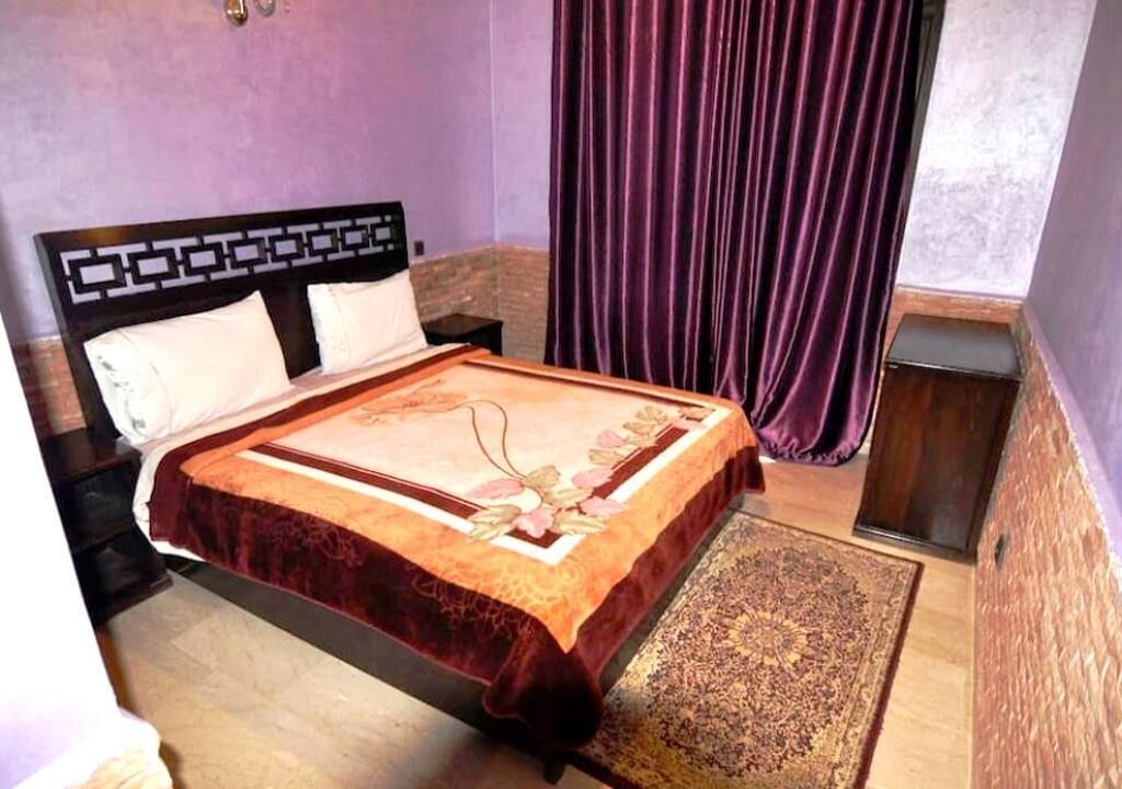 Une chambre à coucher avec un lit, des tables de chevet, un tapis et des rideaux violets.
