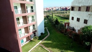 Un immeuble à plusieurs étages doté de balcons, d’une cour verdoyante et offrant une vue sur un quartier résidentiel.