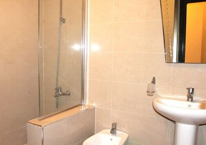 A bathroom with a glass shower enclosure, a white sink, and a mirror above the sink.
