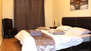 Una camera da letto con un letto, una sedia, un comodino e un quadro appeso al muro.