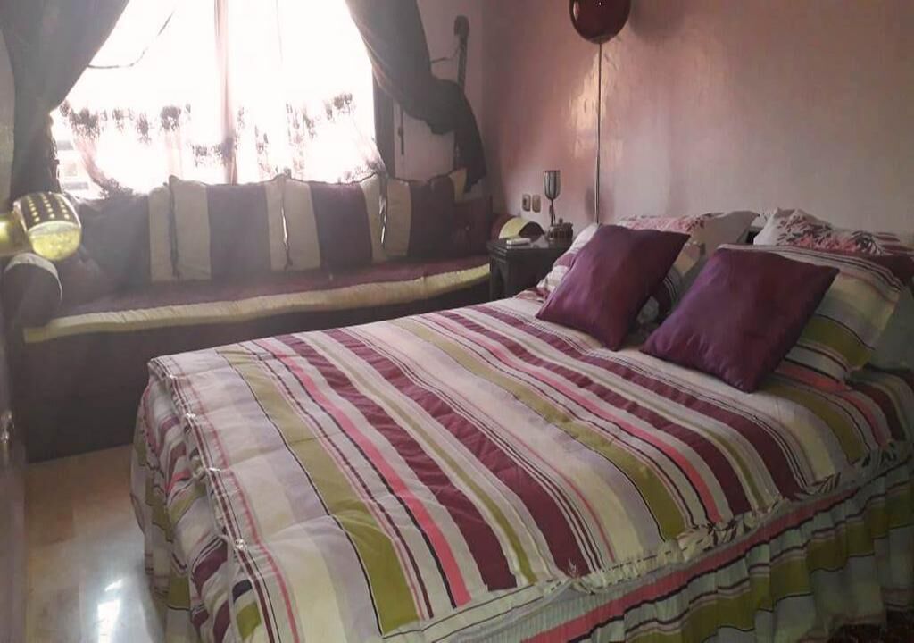 A bedroom with a bed, a sofa, and a window with curtains.