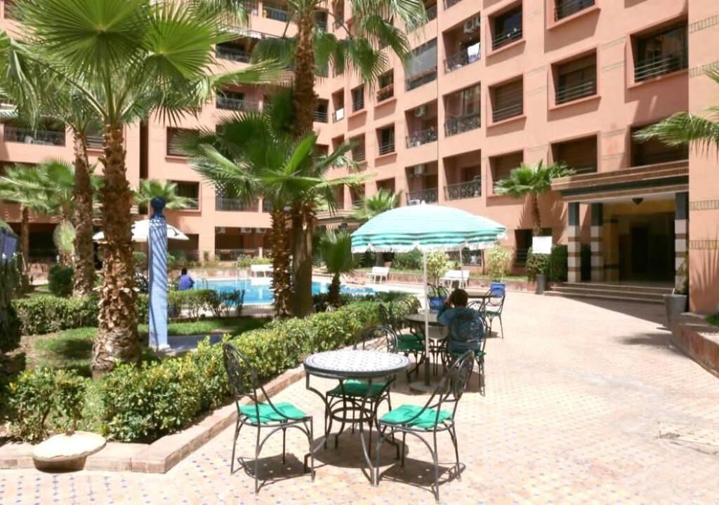 A courtyard with outdoor seating, palm trees, and a pool.
