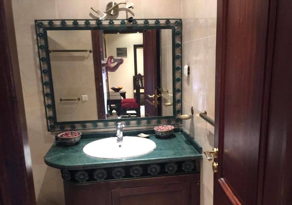 A bathroom with a green marble sink, a large mirror with a decorative frame, and two bowls on the counter.