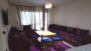 Ein Wohnzimmer mit einer Sofagarnitur, einem Esstisch mit vier Stühlen und einem kleinen runden Tisch.