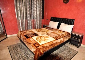 Un dormitorio con una cama grande, una mesita de noche, un espejo y una cortina.