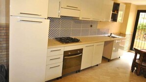 Una cocina con armarios blancos, salpicadero de azulejos y horno empotrado.