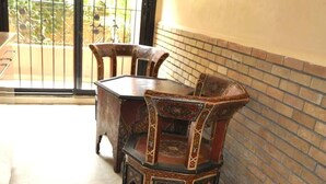 Un comedor con mesa y sillas de madera, una pared de ladrillo y vistas a través de un ventanal.